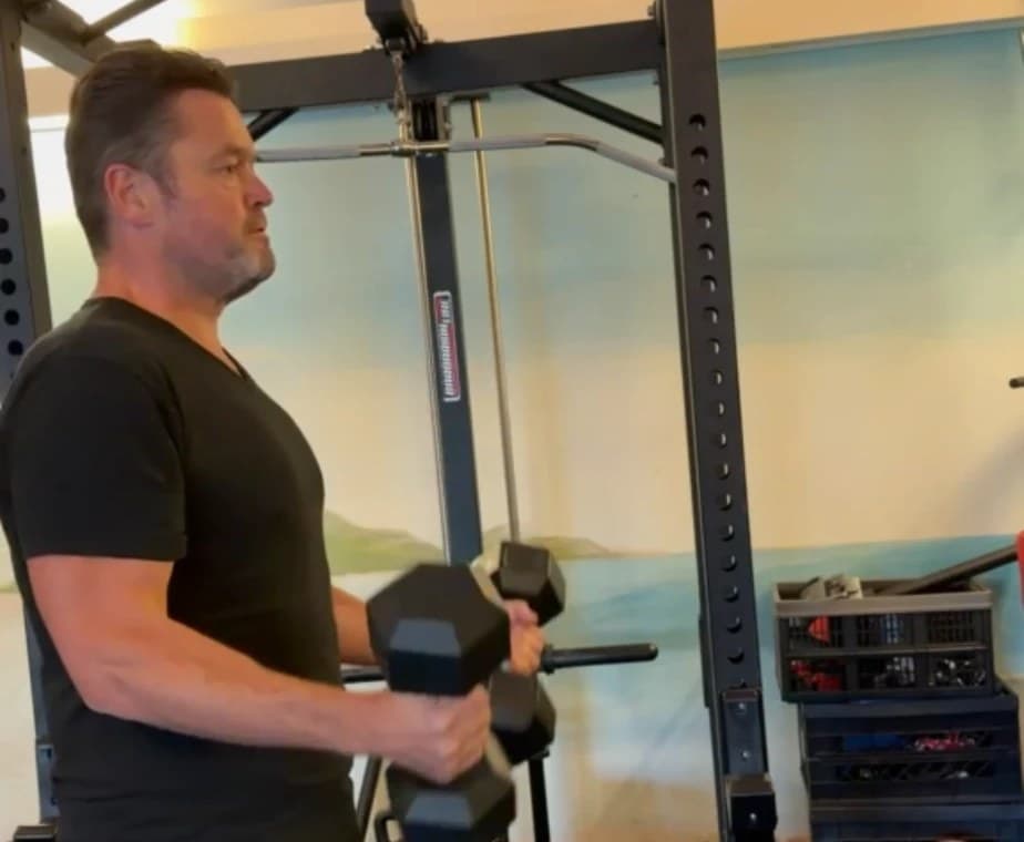 Frans Duijts doet krachttraining met dumbbells in zijn gym thuis